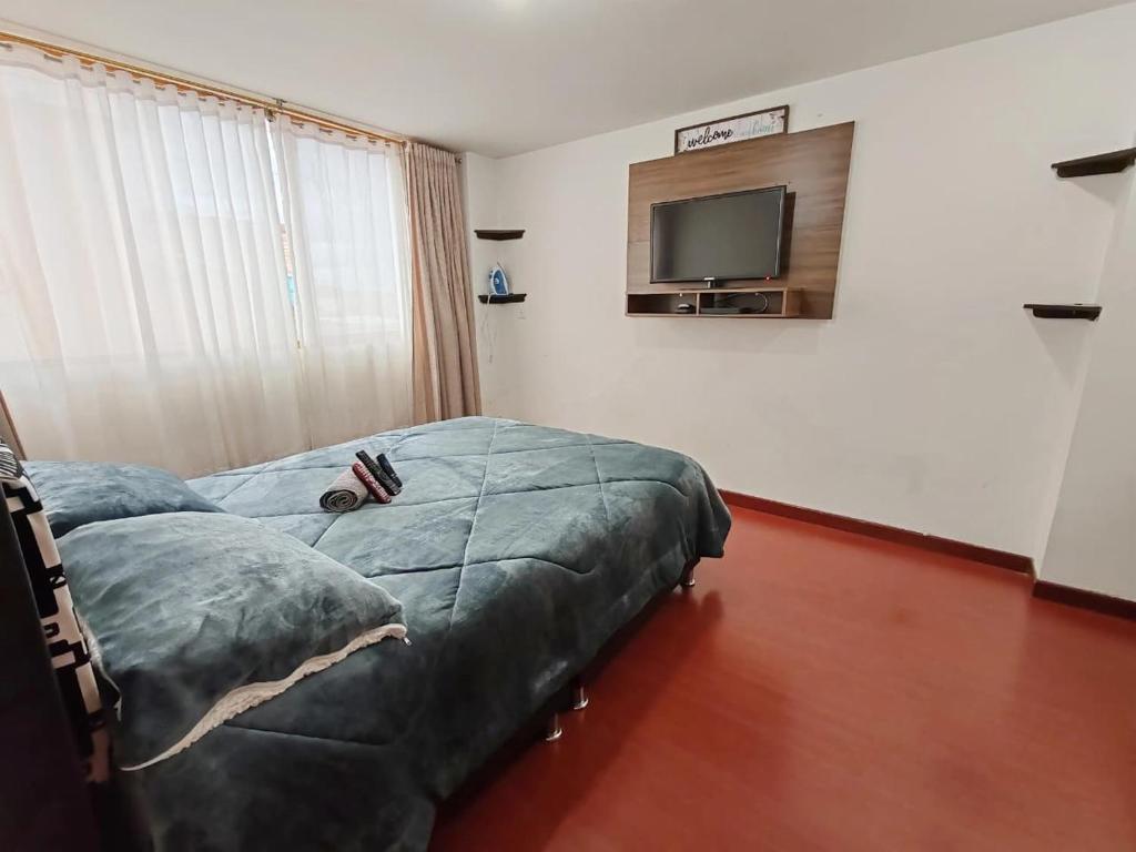a bedroom with a bed and a flat screen tv at Apartaestudio céntrico y acogedor con cocina y WiFi Tunja in Tunja