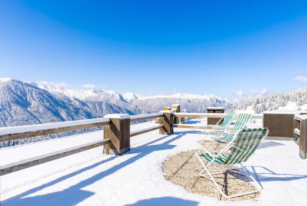 two chairs on a snow covered balcony with a view of mountains at Hostdomus - Rooftop Deluxe Suite in Sestriere