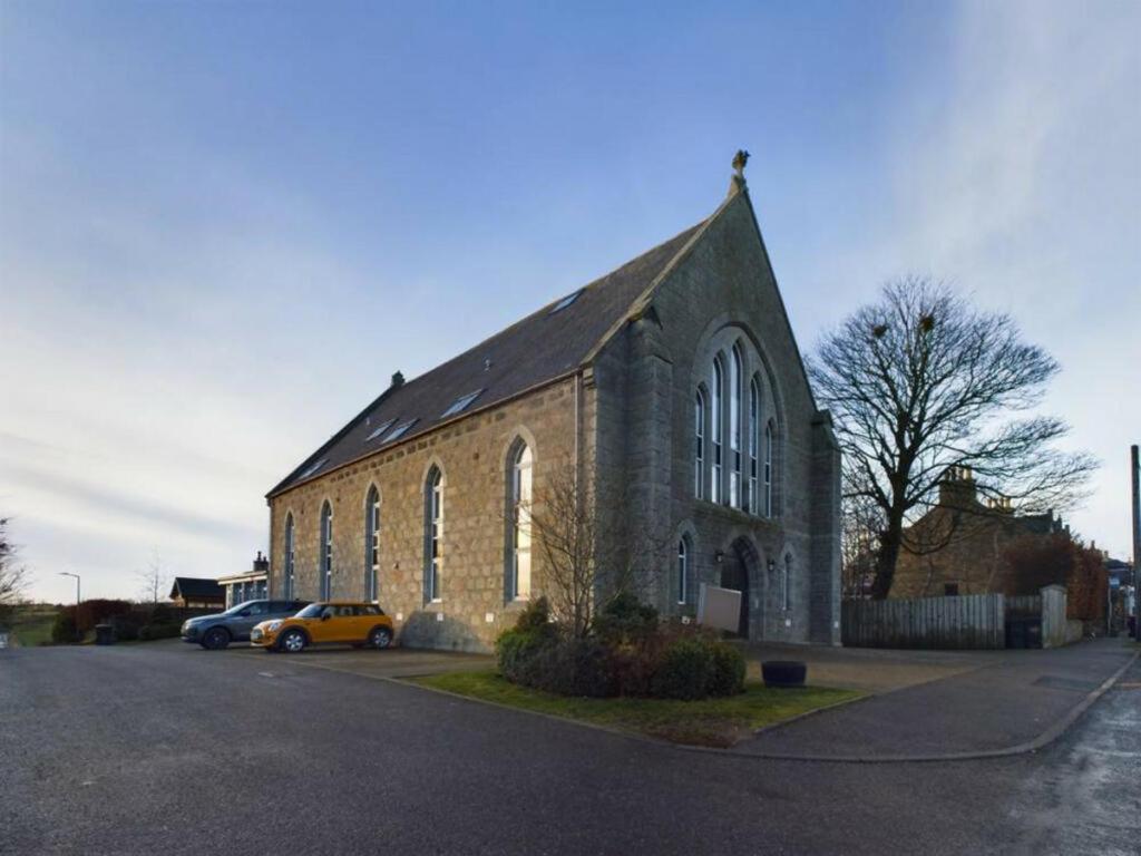 uma igreja com dois carros estacionados em frente em Turfhill House em New Deer