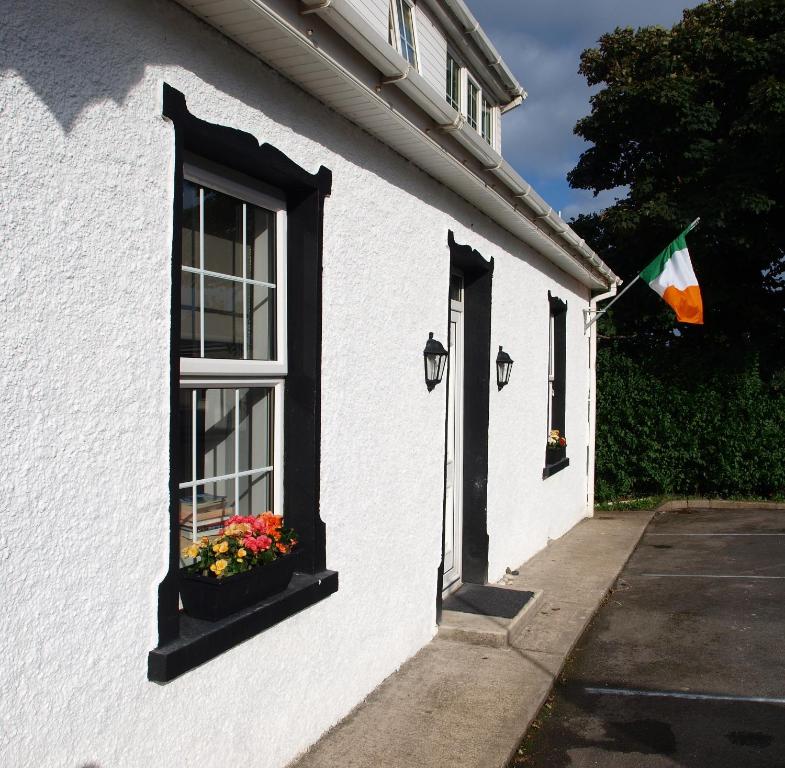 a white building with a window and a flag at The River House Self Catering Apartment in Dungloe