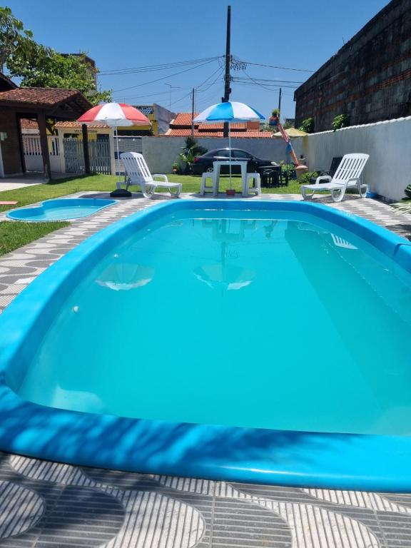 una piscina blu con due sedie e un ombrellone di Hostel Sepumpá Sepápum a Itanhaém