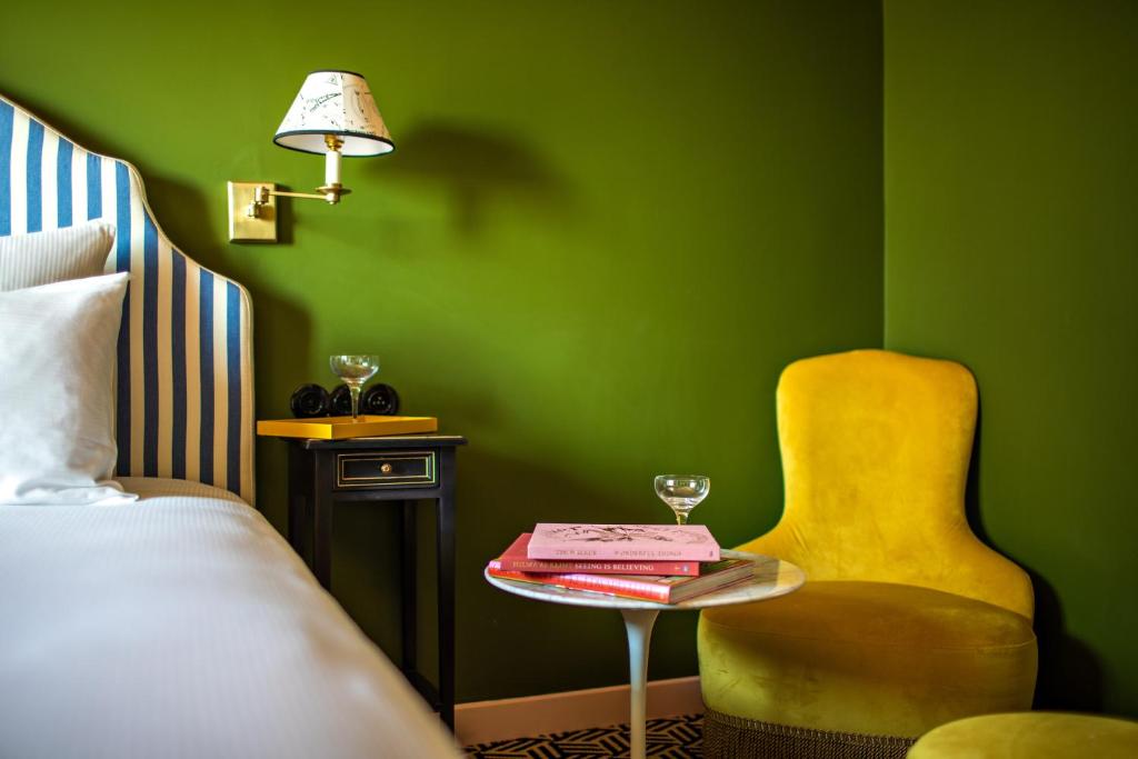 Hôtel Les Deux Gares & Spa في باريس: غرفة نوم خضراء مع كرسي أصفر وطاولة