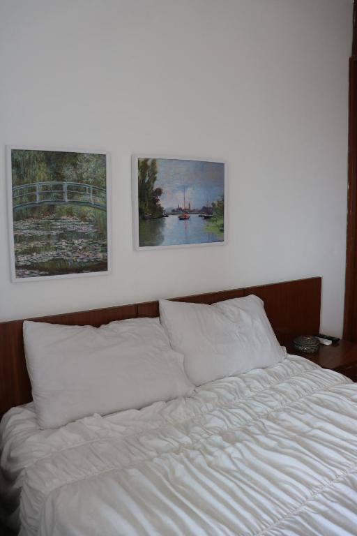 een wit bed met twee foto's aan de muur bij Ocean Flat vista mar in Vila Velha