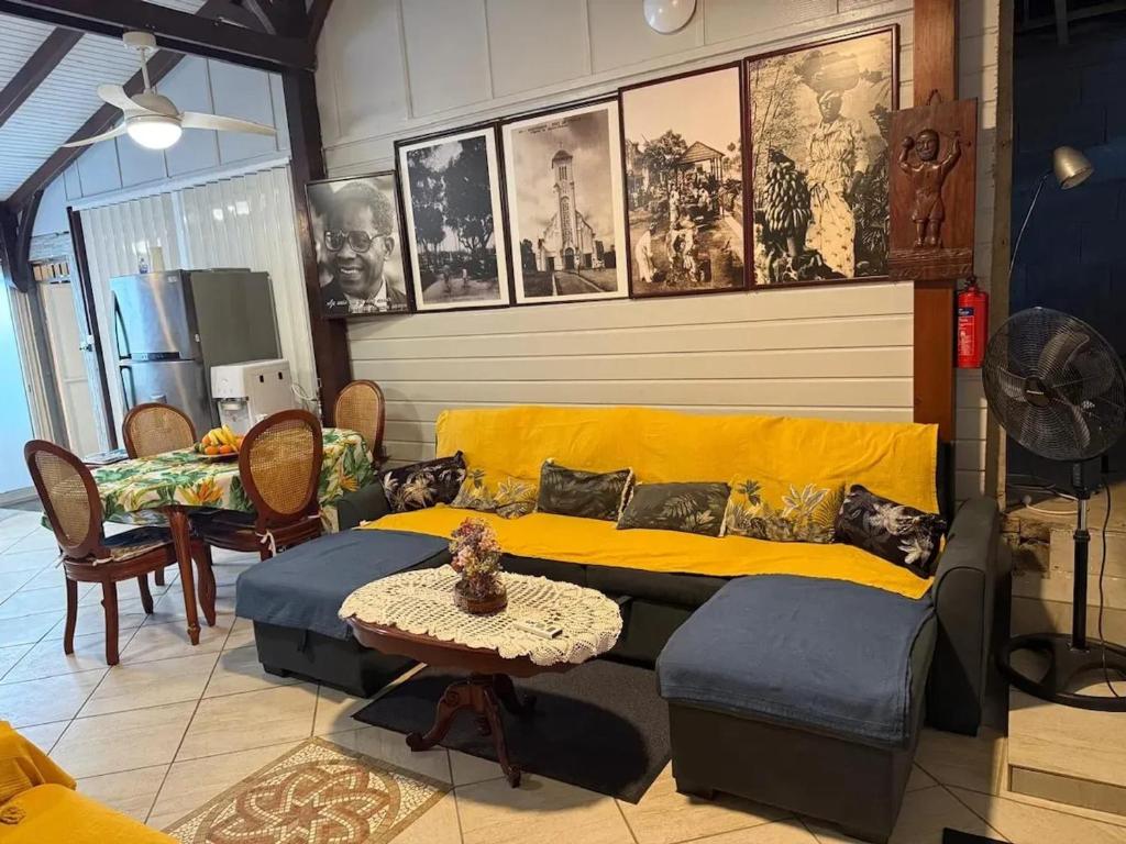 a living room with a yellow couch and a table at Maison charmante à Fort-de-France avec équipements modernes in Fort-de-France