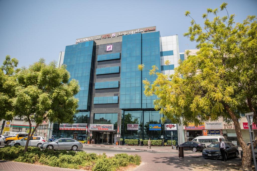 un gran edificio de cristal con coches estacionados frente a él en Saffron Boutique Hotel, en Dubái