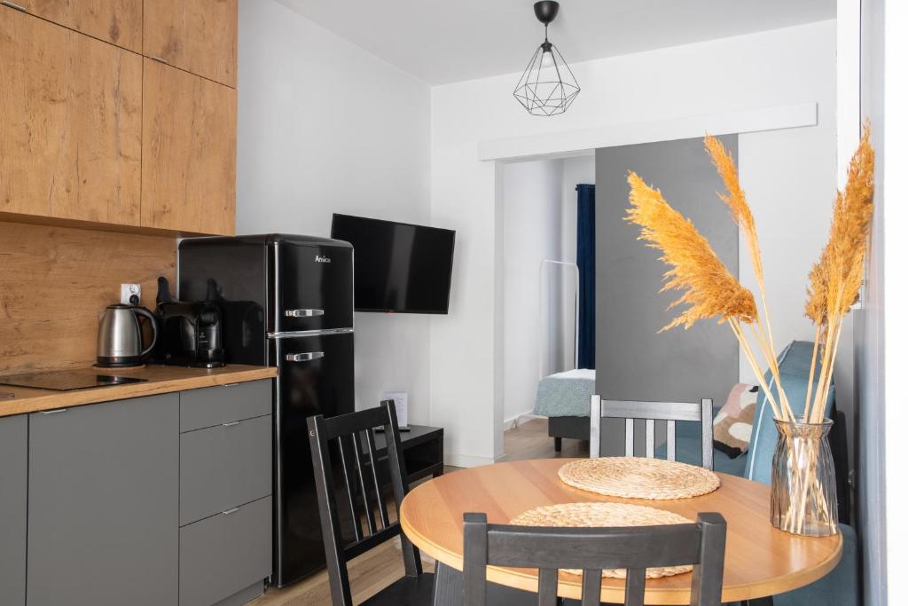 a kitchen with a table and a black refrigerator at ADLER CHILL Apartments in Łódź