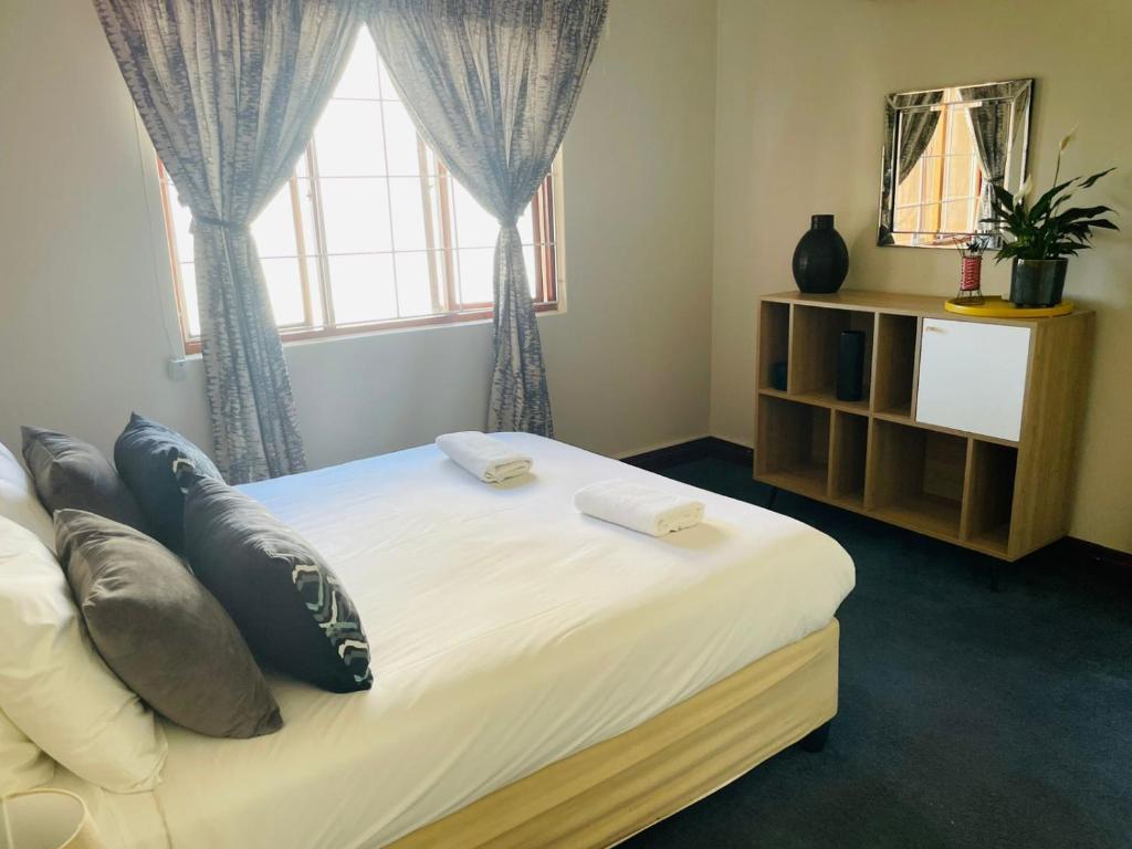 5 OYSTER COTTAGE في ديربان: غرفة نوم بها سرير مع وسائد ونافذة