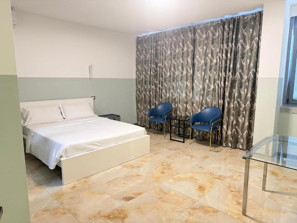 ein Schlafzimmer mit einem Bett und zwei blauen Stühlen in der Unterkunft HHBB hotel in Padua