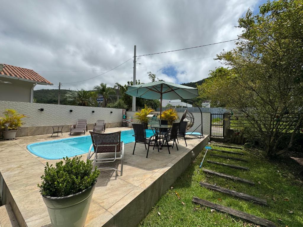 a patio with a table and chairs and an umbrella at Minha Casa Palmas 2 in Governador Celso Ramos