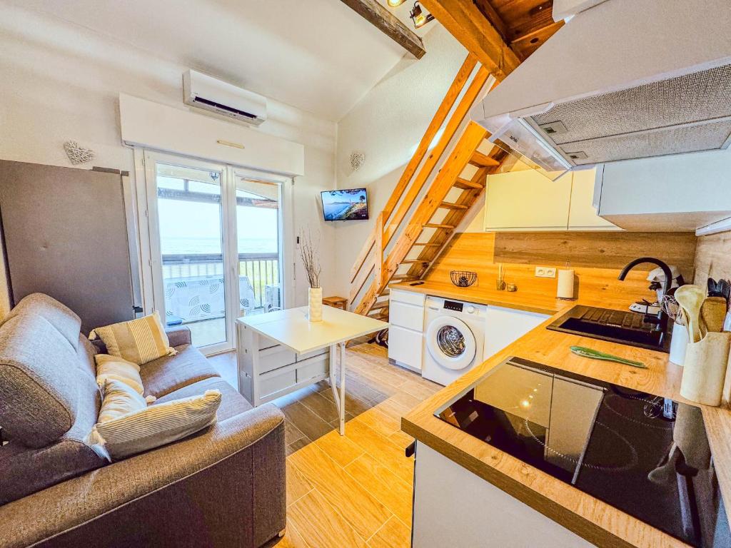 a kitchen and living room with a couch and a table at Escale aux tropiques - Vue mer in Saint Cyprien Plage