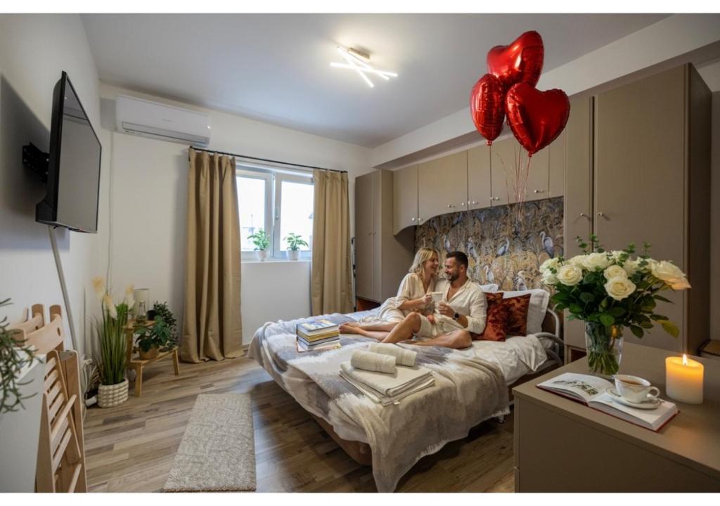 un uomo e una donna seduti su un letto con dei palloncini di Cozy Studio Retreat - Quiet, Premium Stay a Timişoara