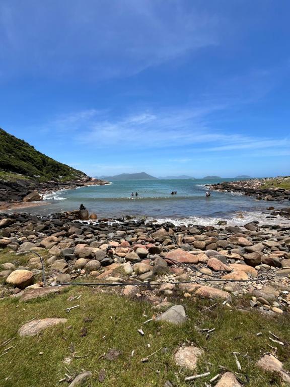 ein felsiger Strand mit Menschen, die im Wasser schwimmen in der Unterkunft Kitnet Pinheira - Praia de Cima in Palhoça