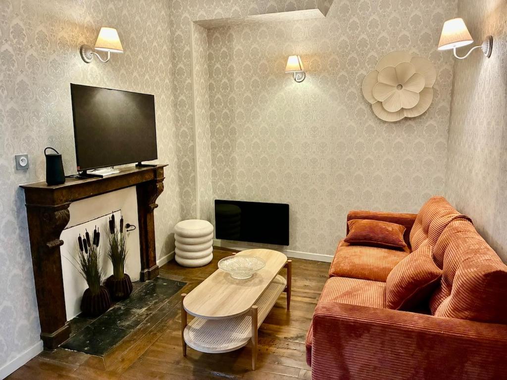 een woonkamer met een bank en een tv bij La Grande escapade T12 in Troyes