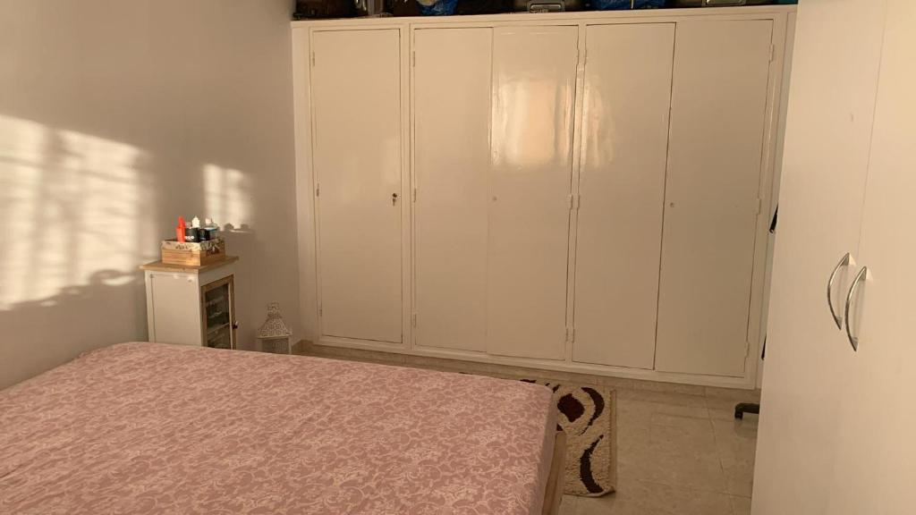 a bedroom with a bed and a white cabinet at App corniche hammamet in Hammamet
