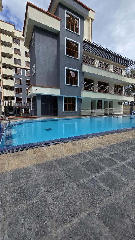 a building with a swimming pool in front of a building at Casaroca Stylish 2br in Nakuru