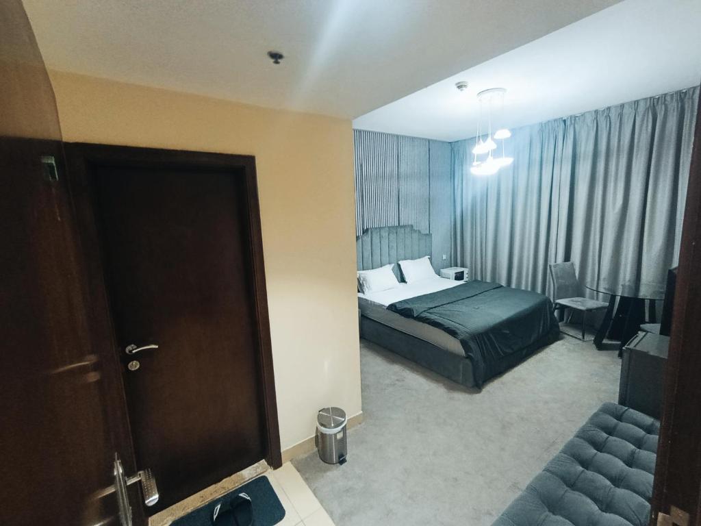 アジュマーンにあるApartHotel Roomsのベッドルーム1室(ベッド1台、ドア、椅子付)