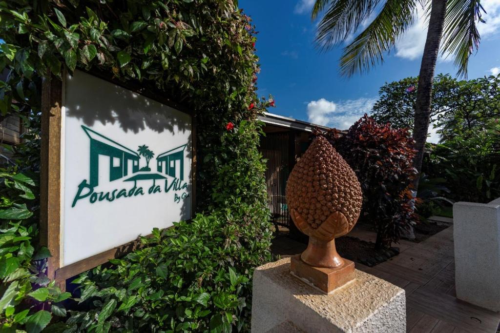ein Schild für ein Ferienresort mit einer Vase davor in der Unterkunft Pousada da Villa in Fernando de Noronha