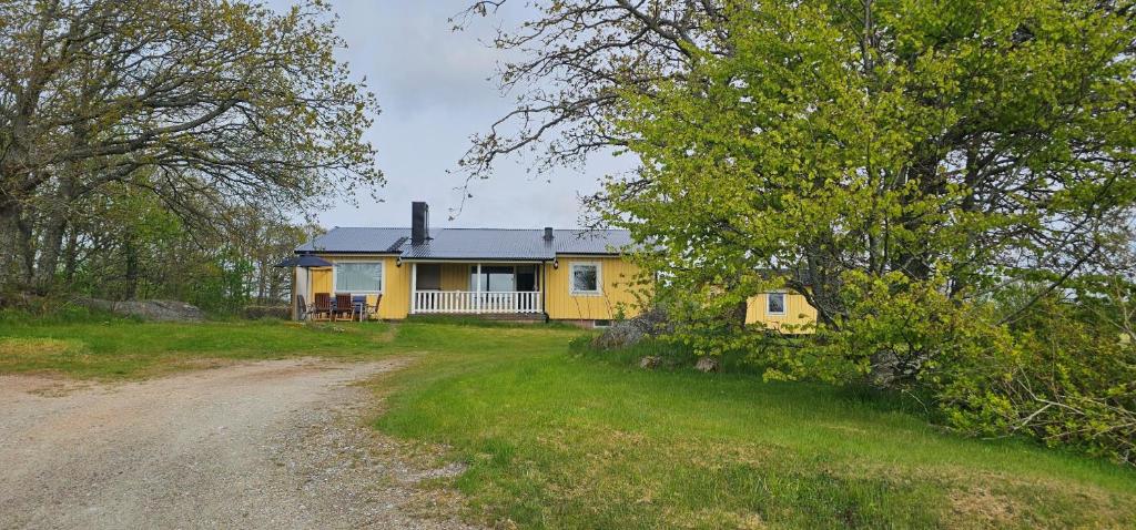 Dogfriendly House in Hjälmvik with Sea Glimpse SE09114 في Haga: منزل أصفر على جانب طريق ترابي