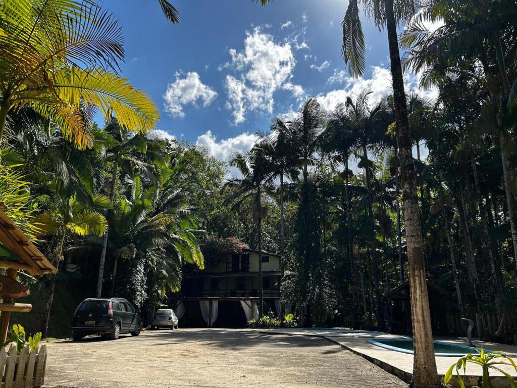a street with palm trees and a car parked on the road at Pousada Quintal Verde in Guabiruba