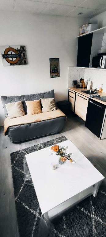 a living room with a white table and a couch at Charmant deux pièces centre Cantimpré3 in Cambrai