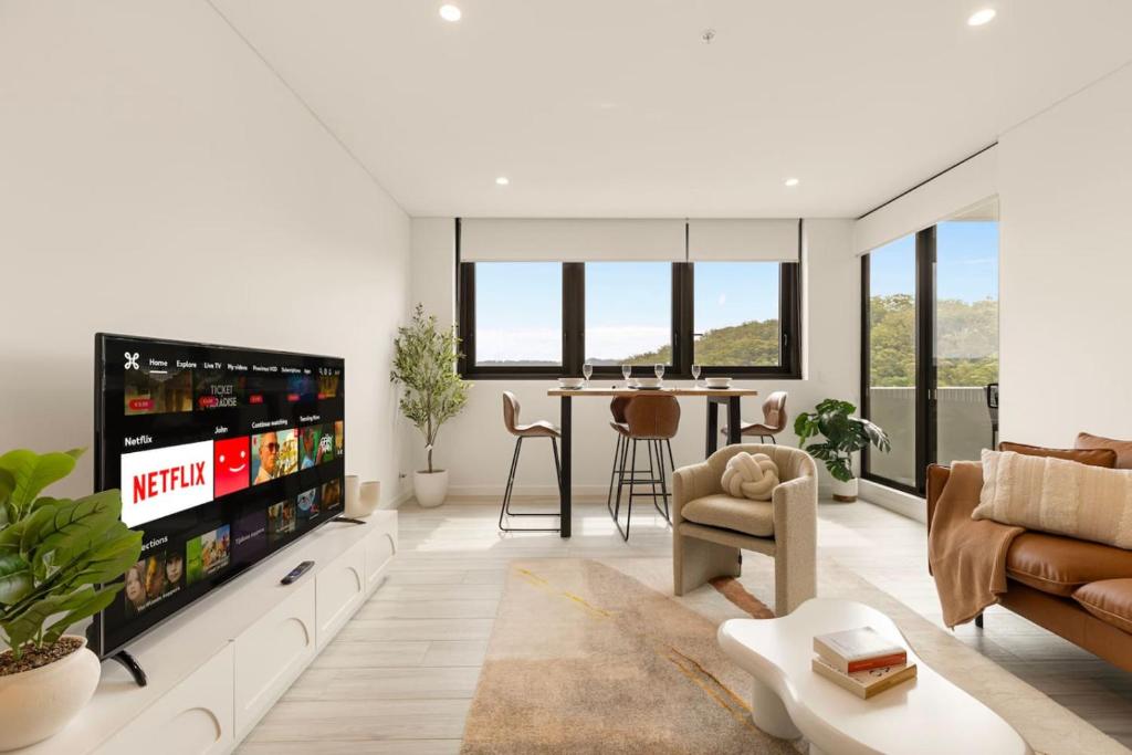 Waterfront Apartment in the Heart of Gosford في جوسفورد: غرفة معيشة مع تلفزيون وأريكة وطاولة