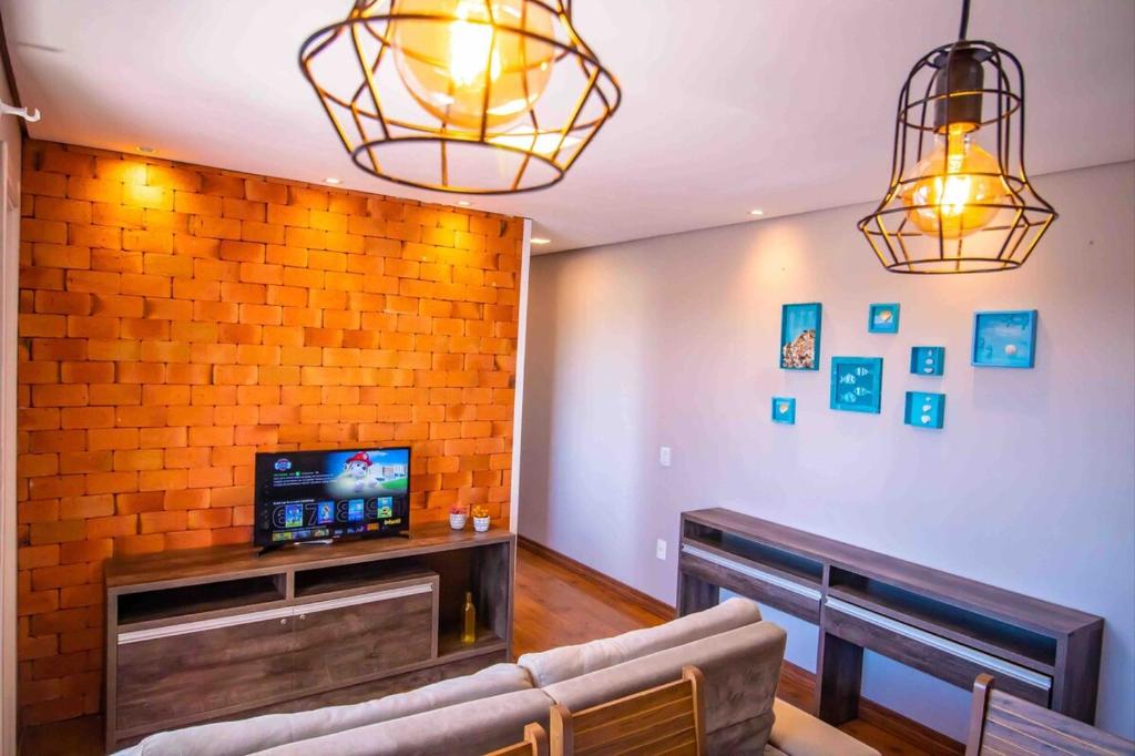 ein Wohnzimmer mit Sofa und Fernseher in der Unterkunft Confortável AP próximo ao parque e praias in Penha
