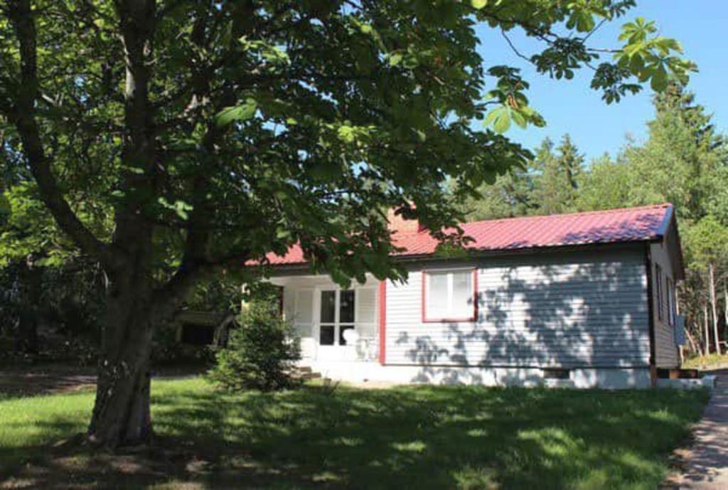 Two cottages by the forest & sea SE09136 في Slussen: منزل صغير أمامه شجرة