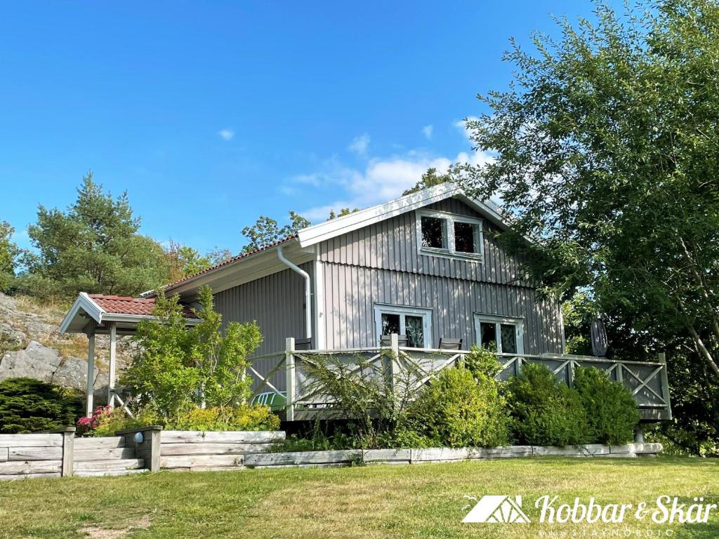 Lovely Cottage near the Resort Nösund SE09111 في Tegneby: منزل رمادي مع سور في الفناء