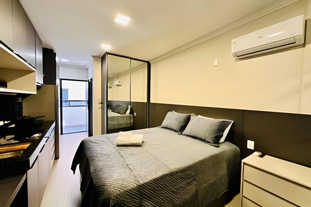 um quarto com uma cama grande com um espelho em Studio Ônix - A poucos passos da Ufu. em Uberlândia