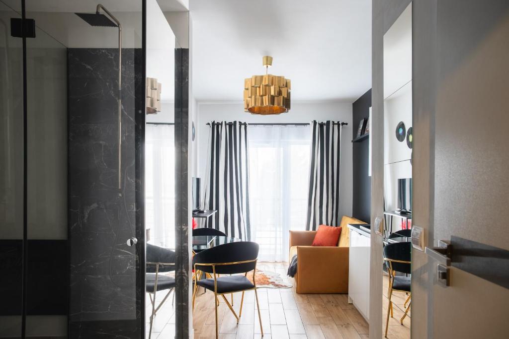 a living room with a table and chairs at Wyjątkowy apartament z prysznicem pośrodku na wyjątkowe wieczory in Łódź
