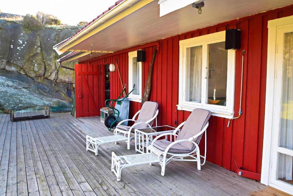 Una casa roja con mecedoras en una terraza. en Two charming cottages in Hälleviksstrand SE09133, en Hälleviksstrand