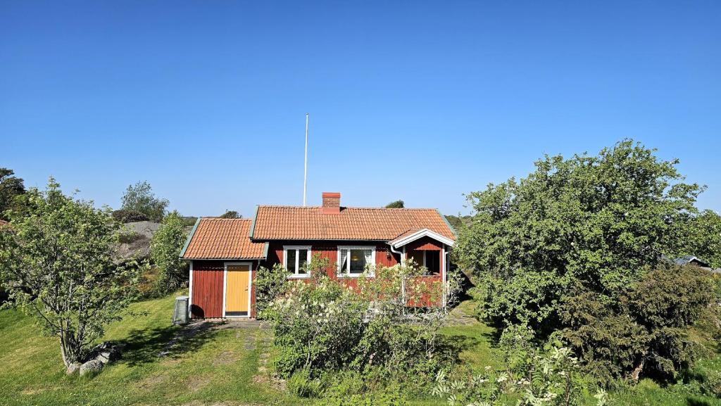 a small red house in a field with trees at Cozy cottage near Hälleviksstrand SE09132 in Hälleviksstrand