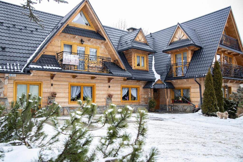 a log home with a black roof in the snow at Pokoje Małgorzatka in Zakopane