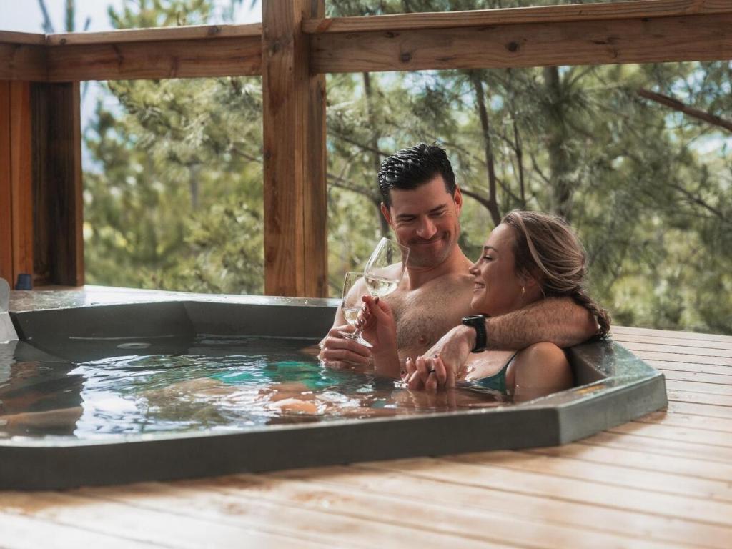 a man and a woman sitting in a hot tub at Barn Owl Cabin at Vrolikheid Landgoed in Tulbagh
