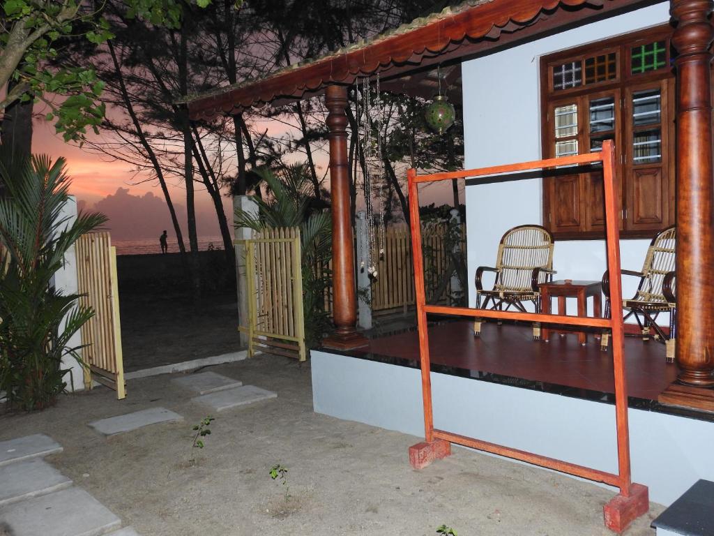 een huis met een veranda met 2 stoelen en een tafel bij Alleppey Beach Garden in Alleppey