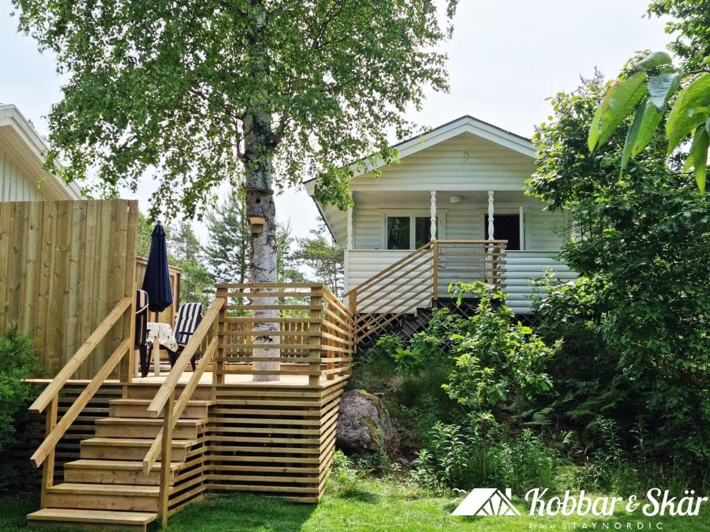 a house with a wooden staircase leading to a deck at Cozy cottage on beautiful Rossö, Orust SE09130 in Röd