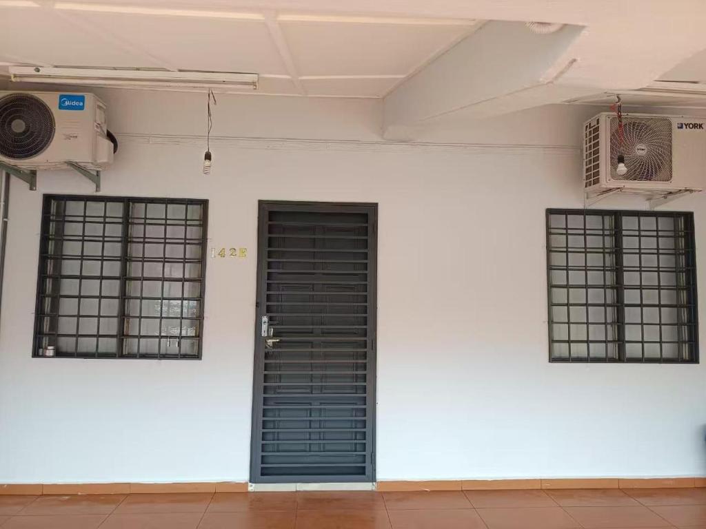 een witte muur met drie ramen en een zwarte deur bij Melaka Kota Home in Melaka
