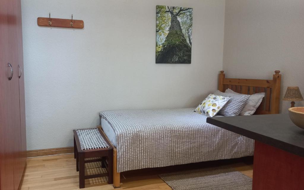 een kleine slaapkamer met een bed en een tafel bij 'The Cape Robin' studio apartment in Hoheizen