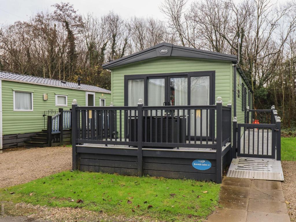 a green and black tiny house with a porch at Foxwood Hideaway in Carnforth