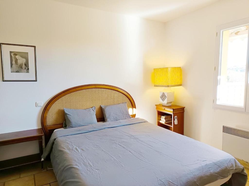 1 dormitorio con 1 cama grande con sábanas azules y ventana en Face à la Citadelle - Jardin & Parking privé, en Forcalquier