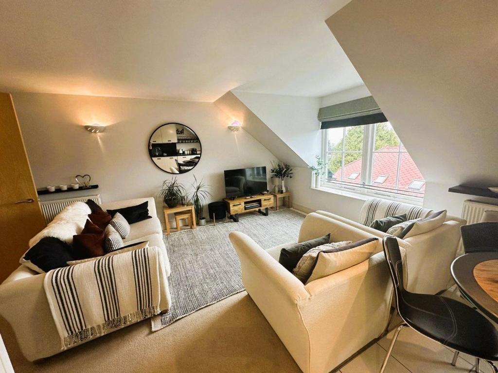 a living room with couches and a table and a tv at Footprints - gorgeous coastal apartment with sea views in Saundersfoot