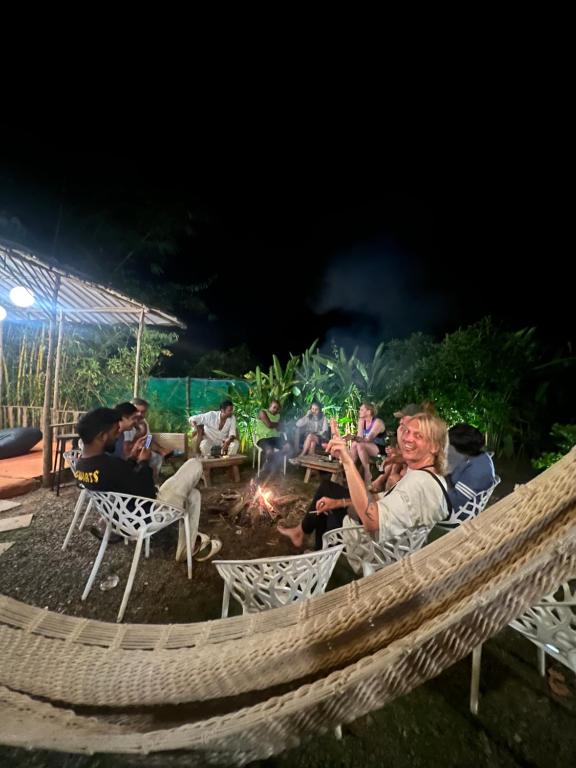 a group of people sitting around a fire at night at The Peace Hostel in Arambol
