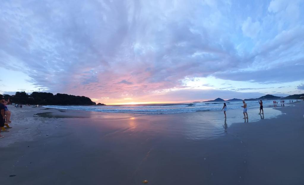 een groep mensen die bij zonsondergang op een strand staan bij Rede Bem Te Vi - Itaguá in Ubatuba