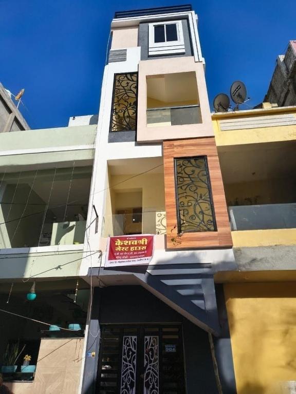 a tall white building with a sign on it at KeshavShree home stay in Ujjain