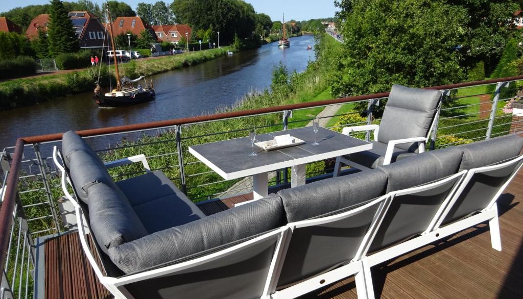 een balkon met een tafel en stoelen naast een rivier bij Ferienwohnung Harlezauber Carolinensiel in Carolinensiel