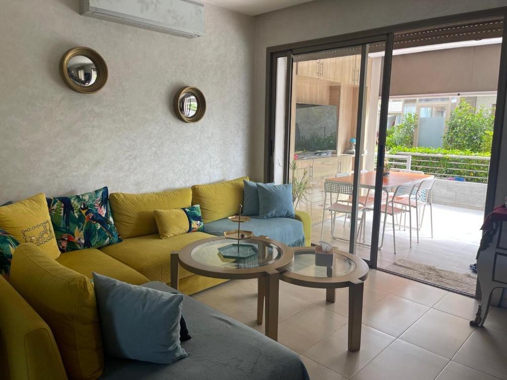 Una sala de estar con un sofá amarillo y mesas. en Apartment with piscine, en Minaret de Mansuria