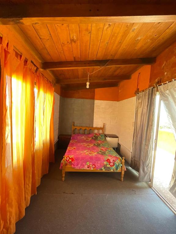 a bed in a room with orange curtains at Cabañas El Pela in Villa Carlos Paz
