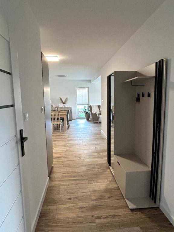 Łeba Garden Apartament في ليبا: ممر فيه ثلاجة وغرفة طعام