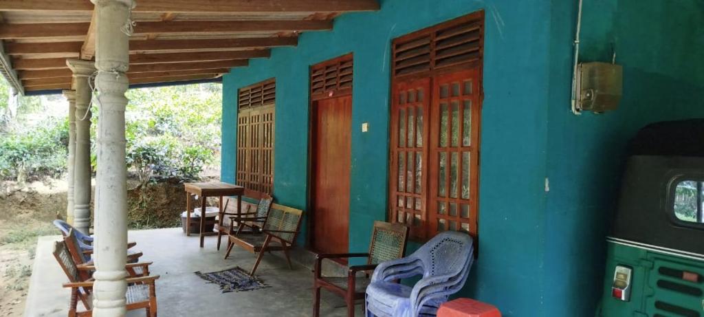 Un porche de una casa con sillas y puertas. en Sinharaja Tour Guide, en Nikawatawana