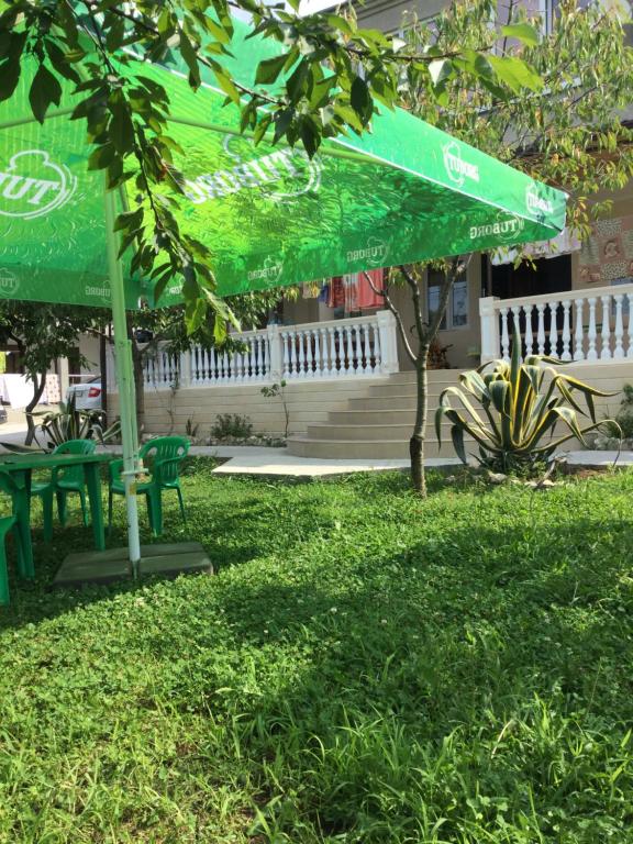 a green umbrella sitting on top of a grass field at Guest house Kabardinskaya 121 in Gagra